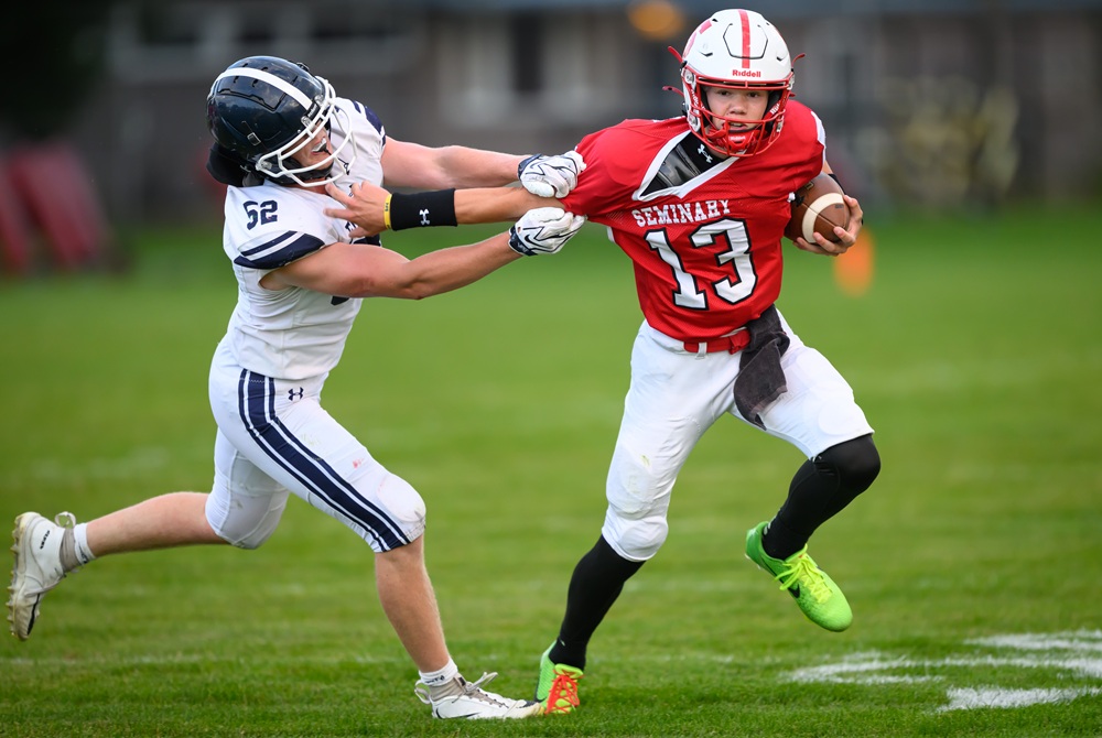 Saginaw Michigan Lutheran Seminary sophomore quarterback Mason Krager (13) scrambles to elude Fowler senior linebacker Jack O’Hare (52) during the second quarter of their season opener Aug. 28 in Saginaw.