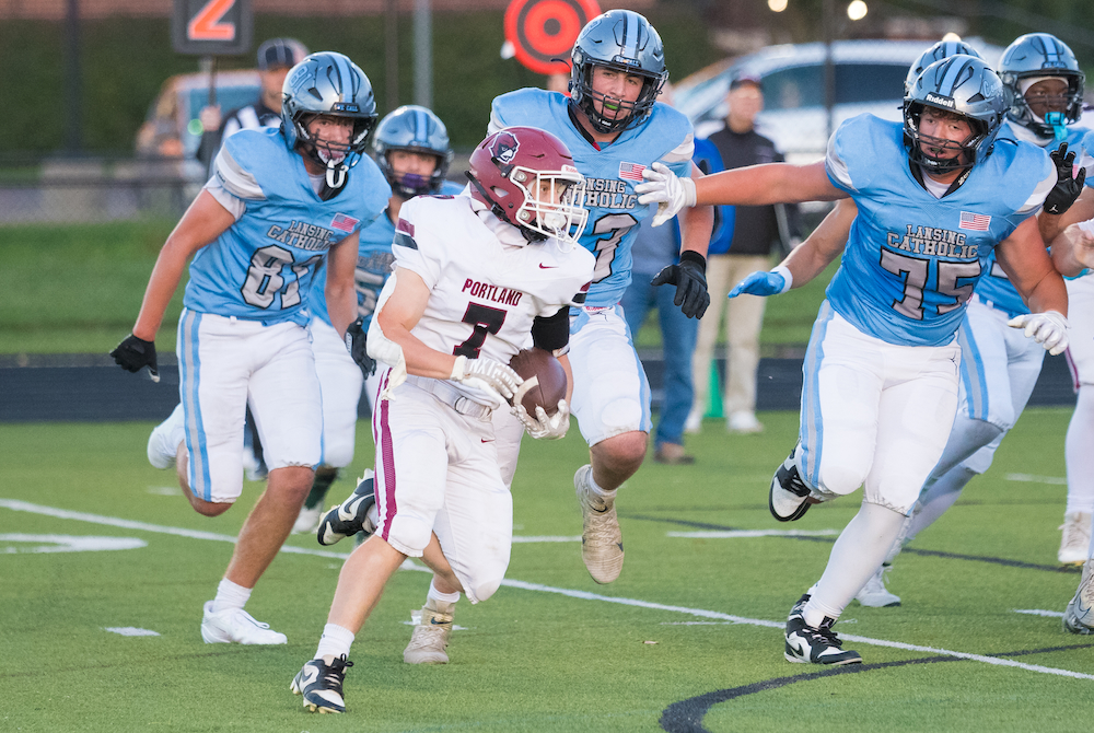 Portland’s Carson Spenski (7) turns a corner with several Lansing Catholic players in pursuit during a 49-14 Raiders win.