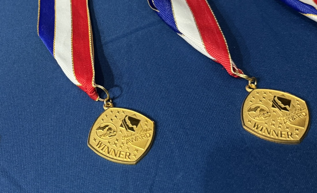 These are two Scholar-Athlete Award medals laying on a table. 