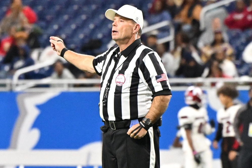 A football referee signals he is assigning a penalty by pointing to that side of the field. 