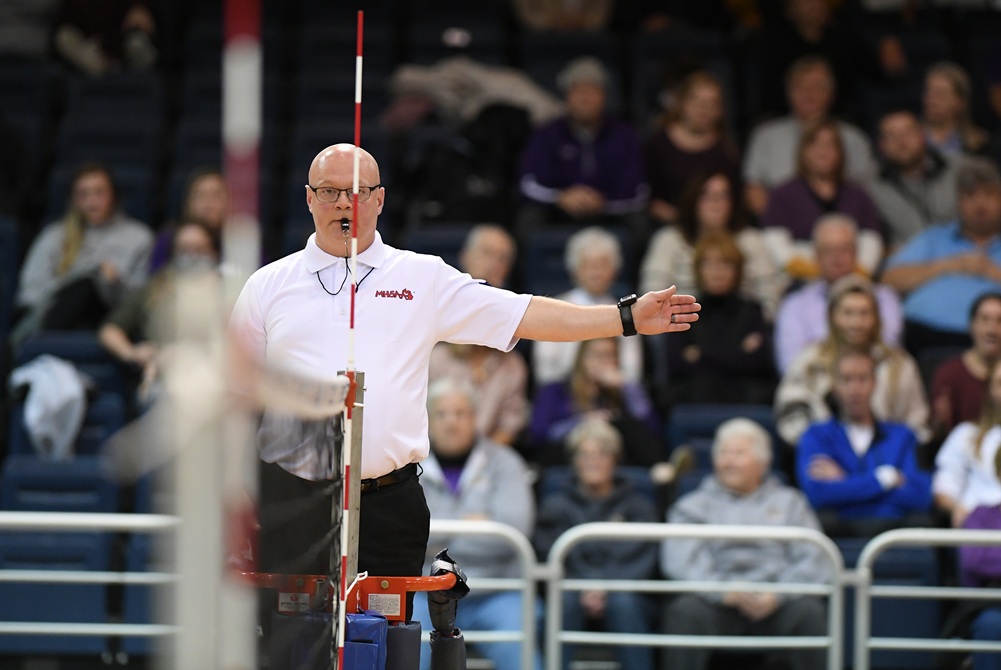 A volleyball official signals from the chair. 