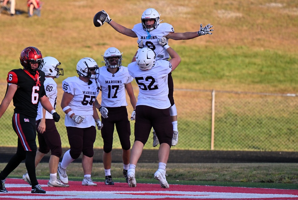 Menominee's Kahne Clarke (52) lifts Jackson Myszak (6) after Myszak runs for the first touchdown of the game during a Sept. 3 win at Marquette.