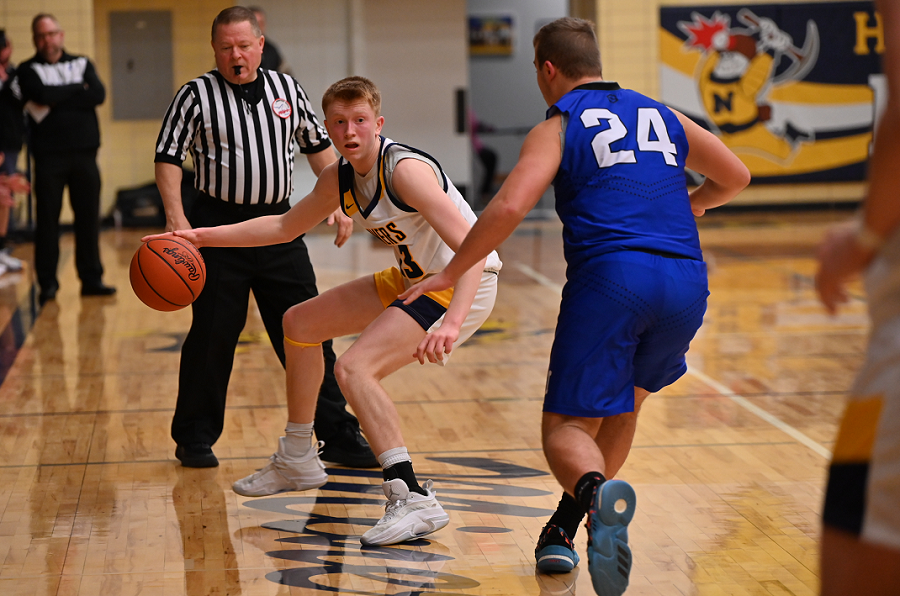Negaunee's Gavin Saunders (23) is defended by Ishpeming's Griffin Argall (24) during the Miners' 63-42 win.