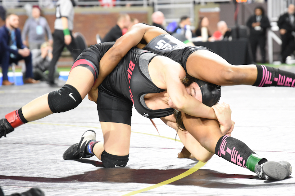Milan’s Angelina Pena, left, and South Lyon East’s Tyler Swanigan lock up in the 130-pound title match.