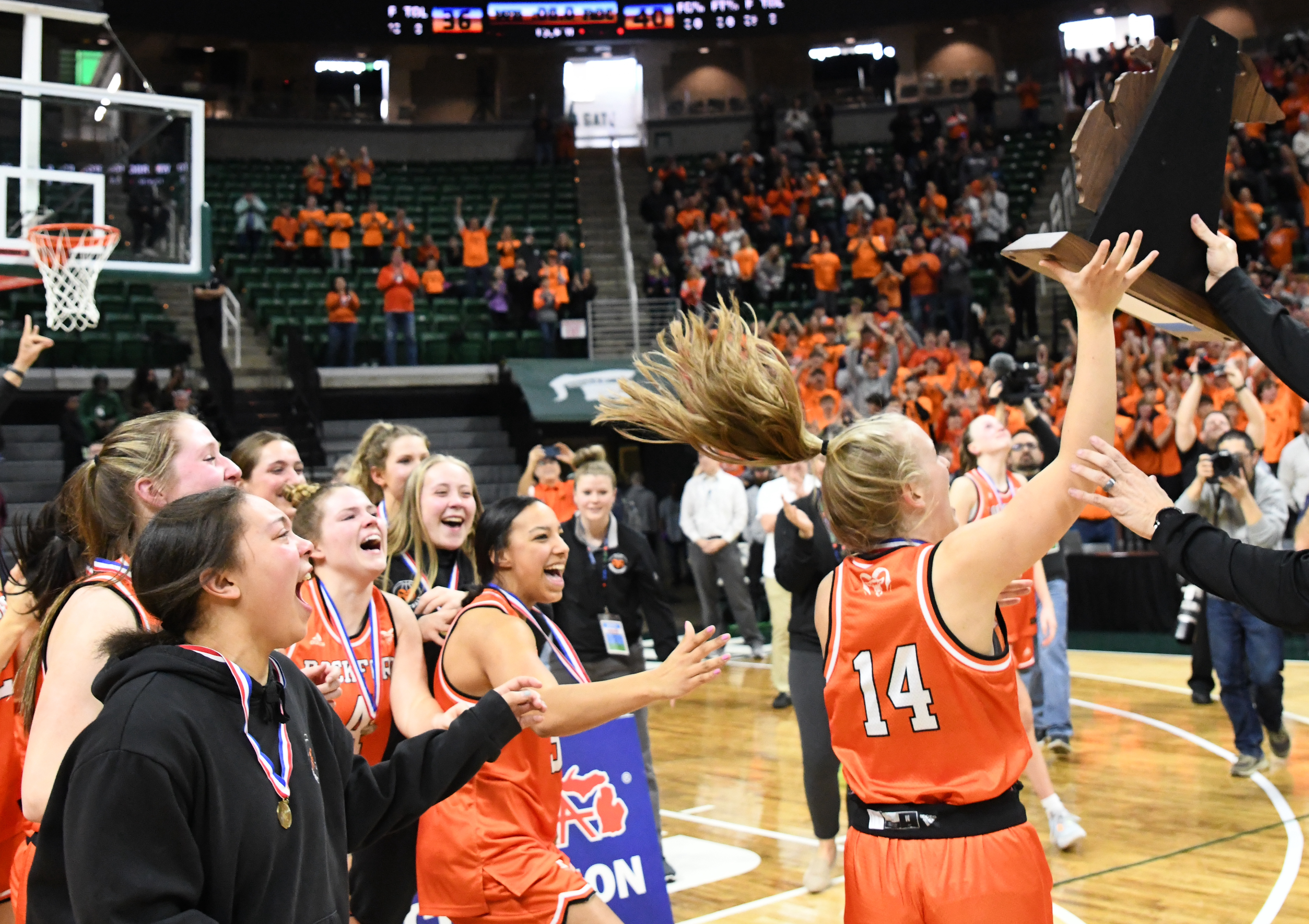 Kayla MacLaren (14) is presented the championship trophy while her teammates celebrate.