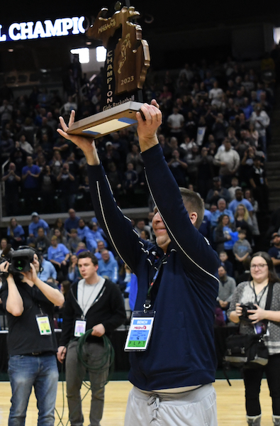 Huskies coach Scott Neumeyer holds up the championship trophy to his team and fans.