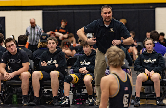 Glen Lake coach Luke Moeggenberg instructs one of his wrestlers on the mat.