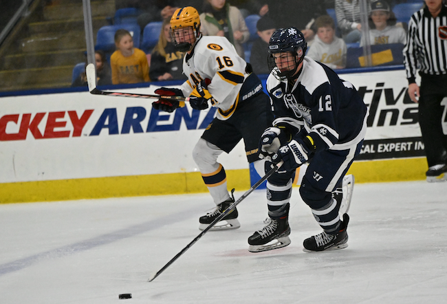 The Cranes’ Nick Timko (12) brings the puck up the ice with EGR’s Charlie Hoekstra in pursuit.