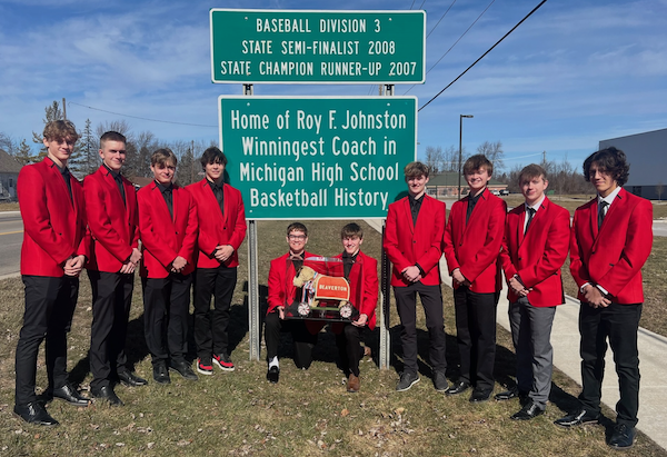 This season’s team stands at the entrance to town with signs announcing the program and coach’s successes. 