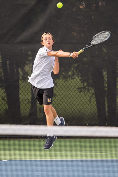 A Trojans player sends back a volley. 