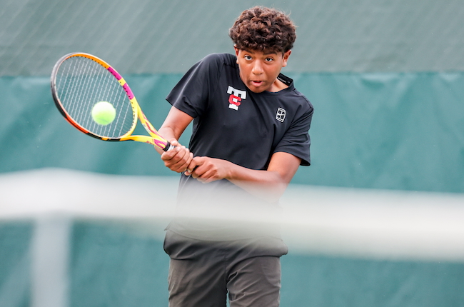 A Troy athlete sends a tennis volley toward the net. 