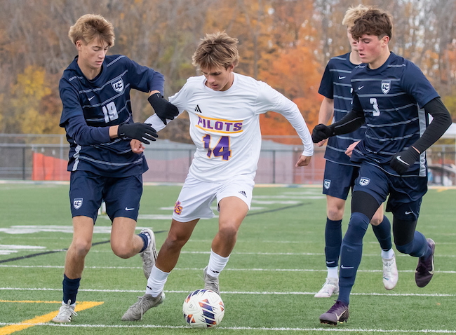 The Pilots’ Andrew Corder (14) controls the ball with Unity Christian’s Landon Crump (19) and Kyler Berghuis (3) working to gain possession. 