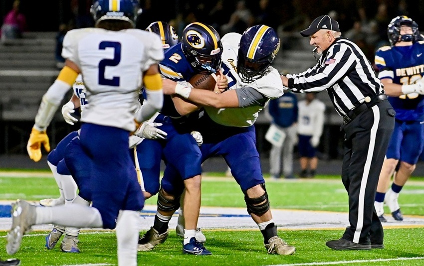 An Owosso defender wraps up DeWitt's Trav Moore (2) during the Panthers' 70-13 win.