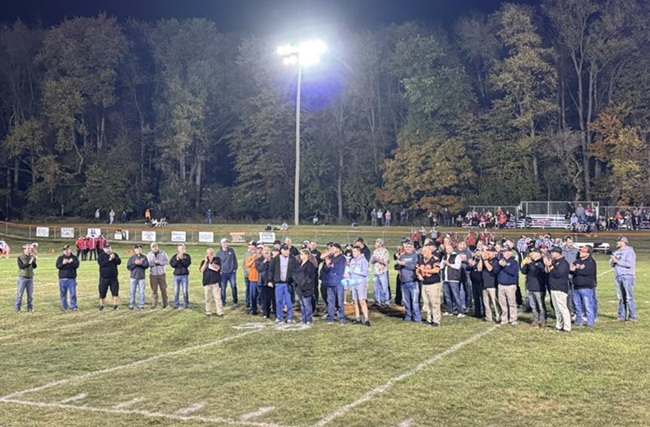 Past Jonesville players line up with retired coach Greg Morrison during the final game.