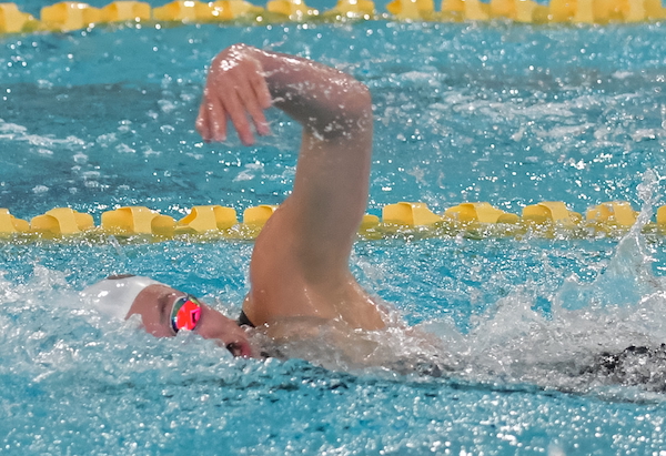 A swimmer competes in freestyle.