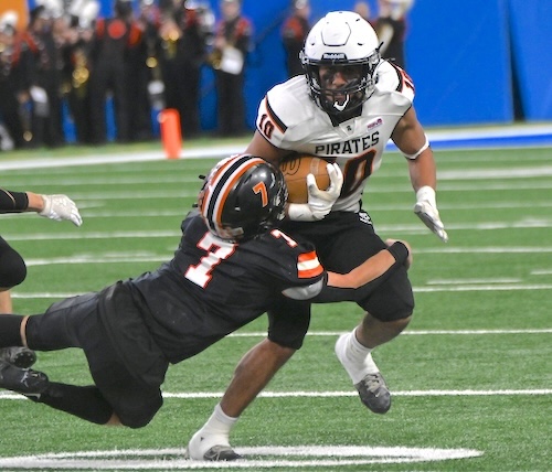 The Pirates’ Benson Harper (10) works to break out of the grasp of Hudson’s Colt Perry.