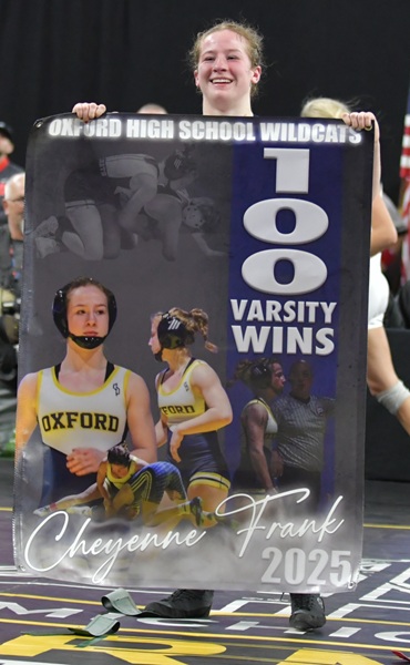 Frank holds up a banner celebrating her 100th victory after the championship win.