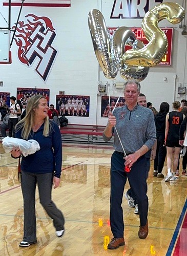 Lusk carries balloons celebrating his 200th win alongside Hanover-Horton teacher and basketball parent Courtney Toteff. 