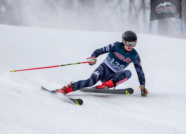 A skier makes a turn heading toward a gate.