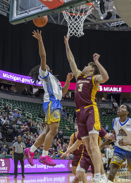 Jaiden Price (5) attempts to get a shot up over the outstretched arms of Menominee’s Tanner Theuerkauf. 