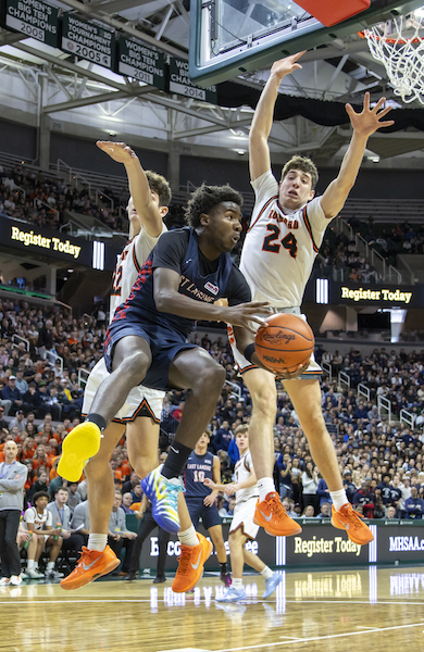 Jake Bascom (24) and Drew Ferwerda (22) wall off East Lansing’s KJ Torbert under the basket. 