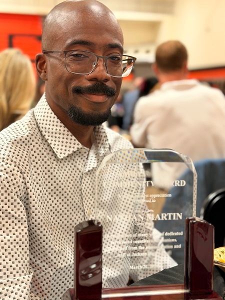 Martin poses for a photo with a community award he received from the school.