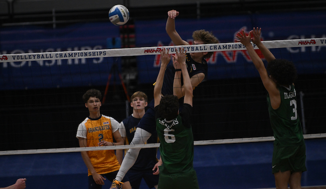 Lake Orion’s Cole Essmann (6) leaps to block a Grand Haven kill attempt.