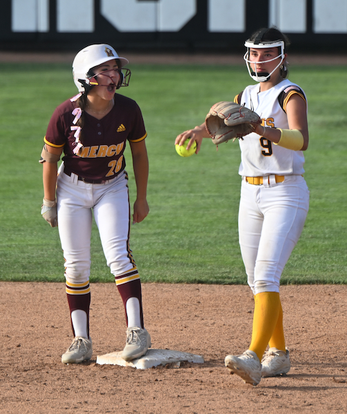 Mercy’s Sophia Chaput (28) yells toward her team’s dugout after reaching second base, while Ogemaw Heights’ Aubrey Evans throws the ball back to the pitcher.
