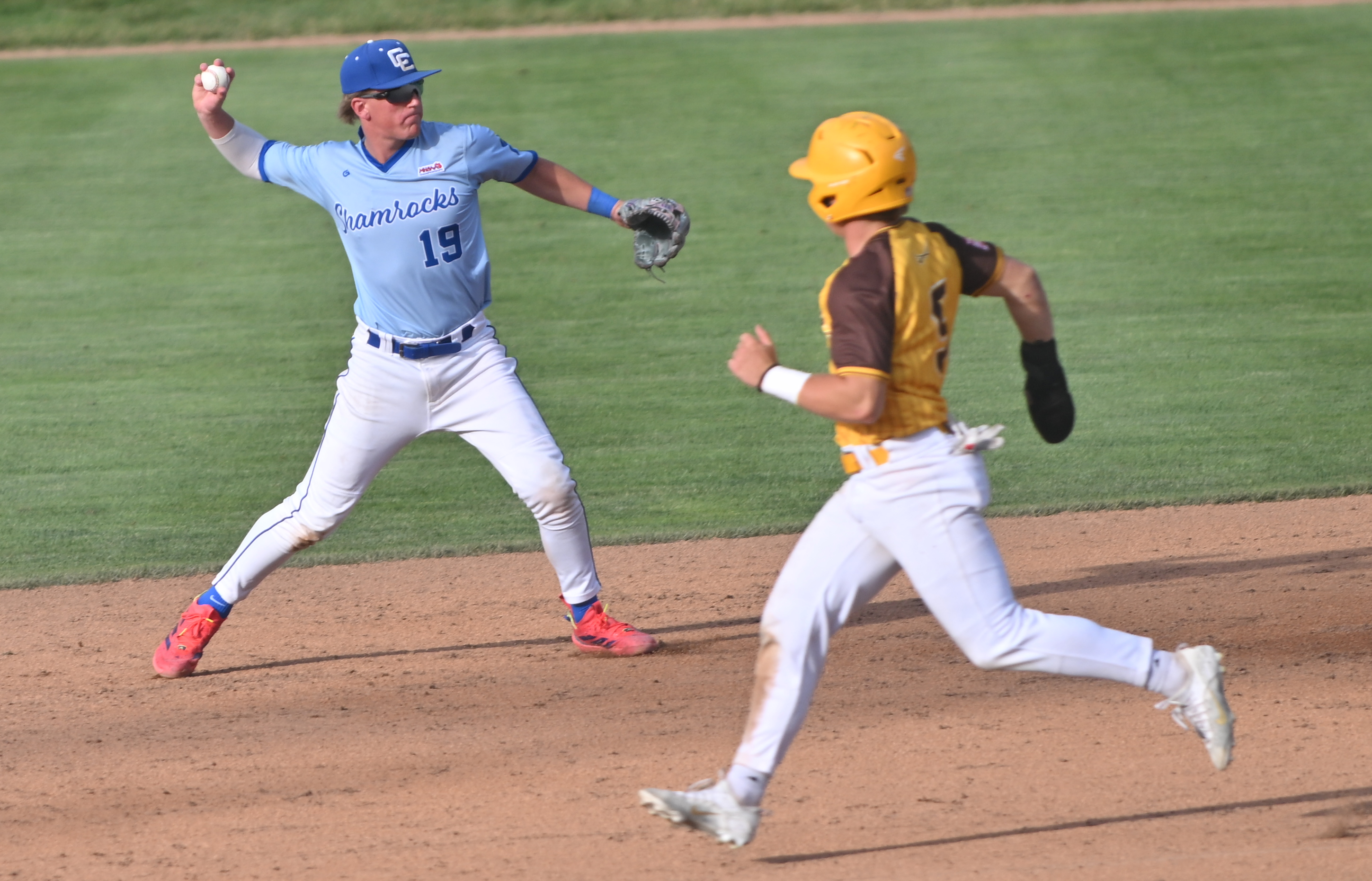 The Shamrocks’ Kyle Davis (19) throws to first base while Adams’ Matt Toeppner attempts to advance.