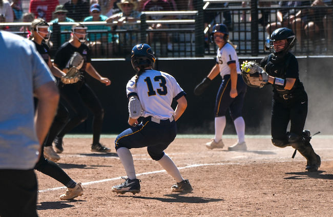 Grand Haven’s Ryley Jeltema is stuck between third base and home as Northern catcher Anna Doyle runs her back.