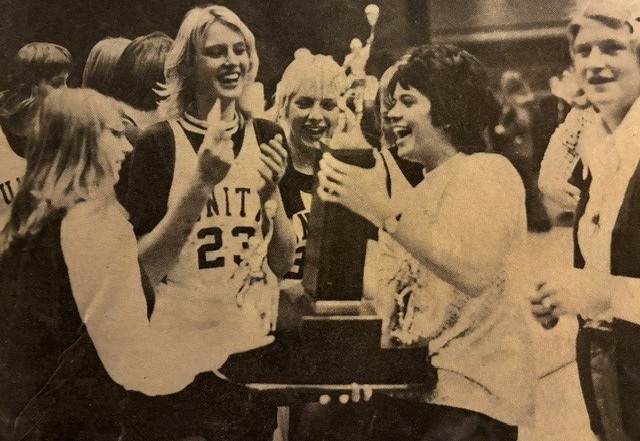 Unity coach Susan Contant holds the championship trophy surrounded by her players after the clinching victory. 