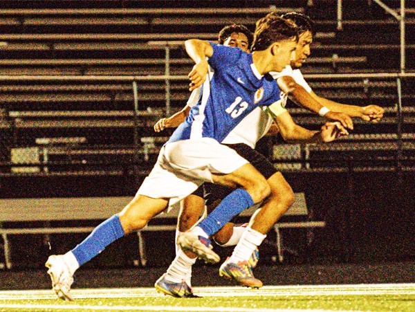 Holley and an opposing defender pursue the ball. 