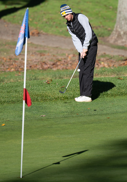 A golfer chips toward the green. 