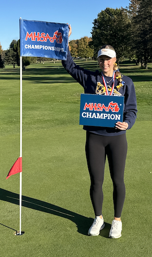 Griswold holds up her championship sign with one hand and a pin flag with the other. 
