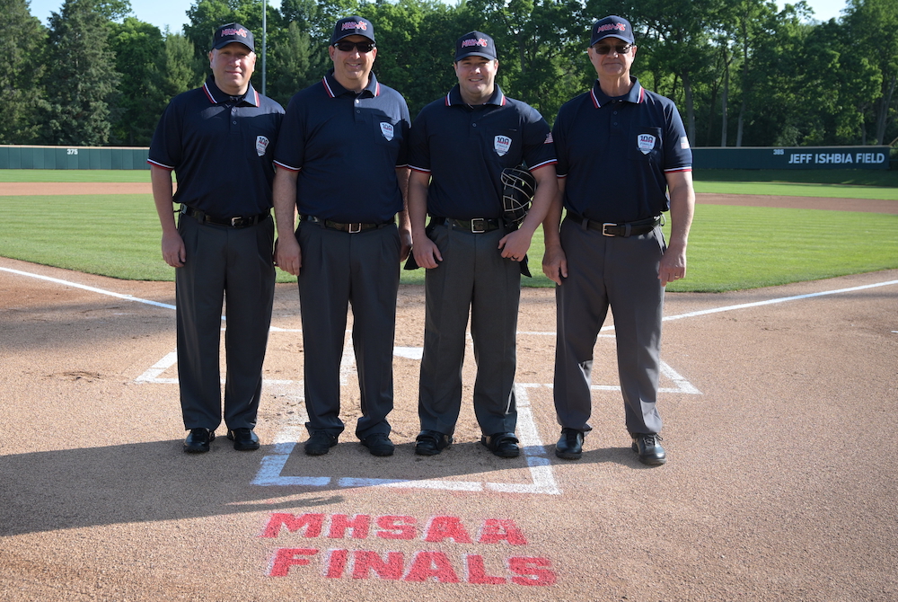 The umpires from the 2025 Division 3 Final take a photo at home plate.