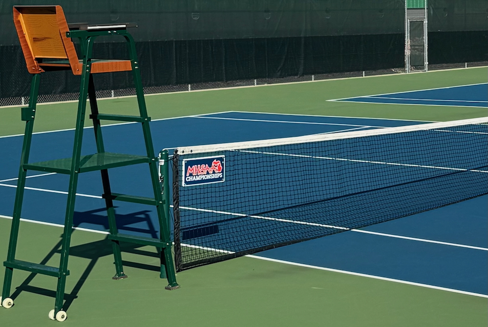 This is a photo of a tennis official's chair and the net with an MHSAA logo attached.